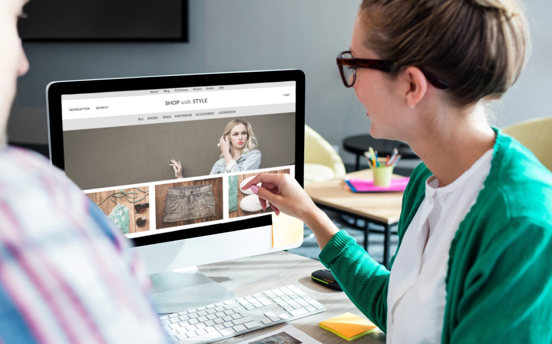 Business woman pointing to desktop screen portraying high-quality images of fashion.